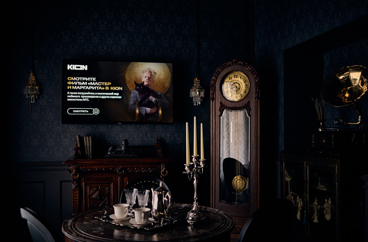 A KION screen built into the room, framed by a grandfather clock and 1930s furnishings